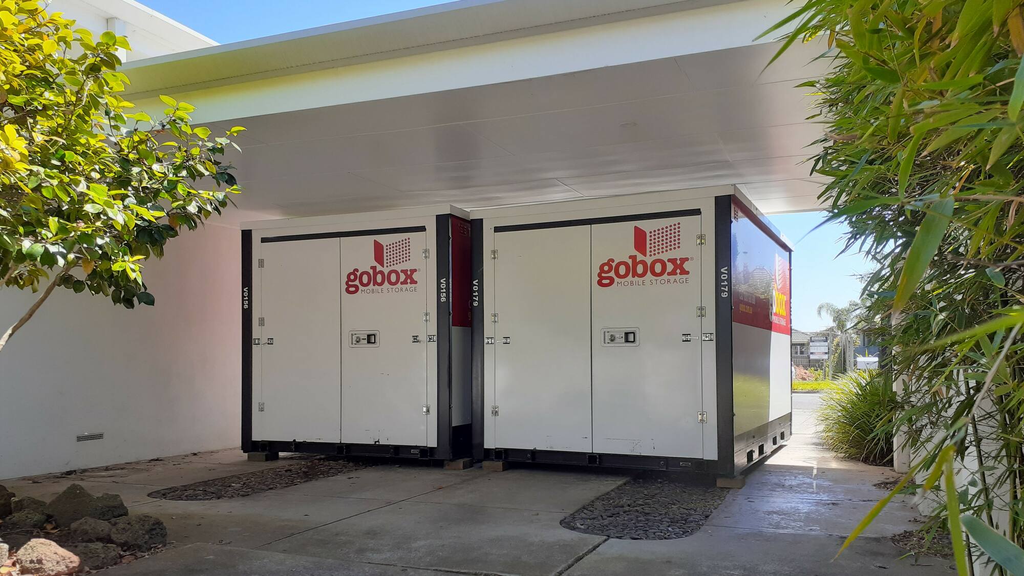 Two gobox mobile storage units parked side by side under a carport